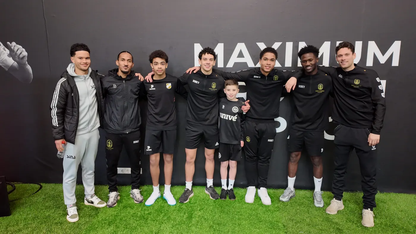 Coaches en spelers van Voetbal Dream Coach samen op de foto voor een zwarte wand